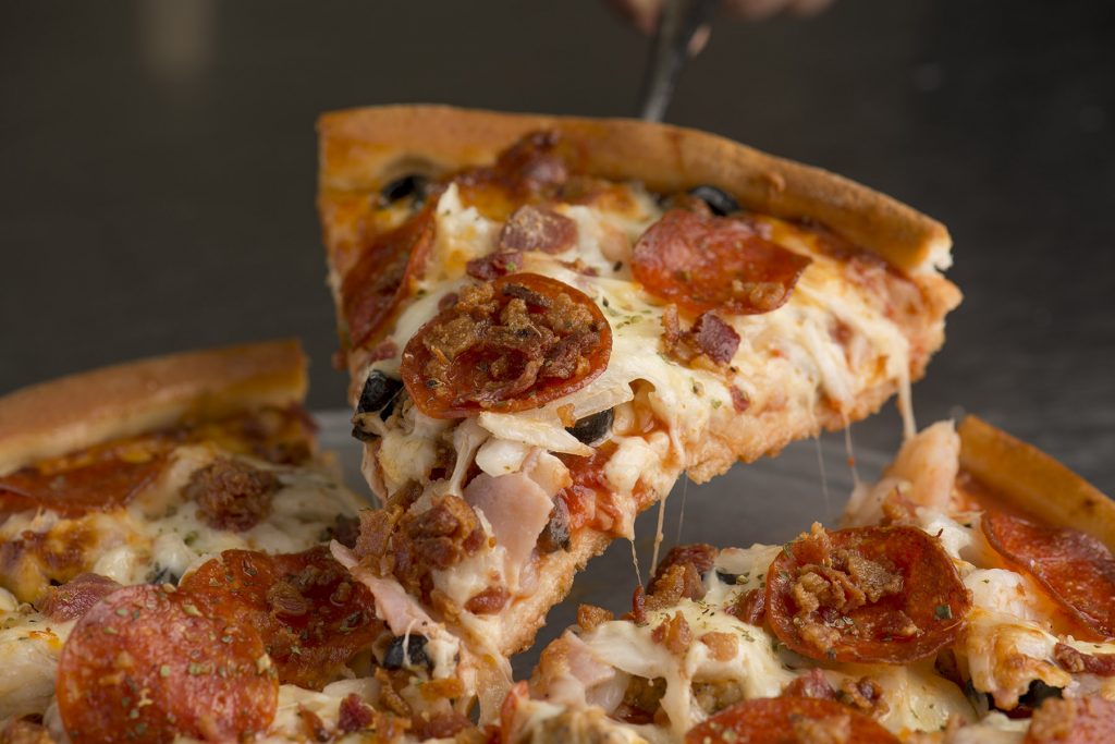 Hilltop pizza slice with melted cheese lifted from a pizza